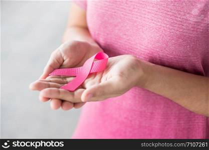 October Breast Cancer Awareness month, Woman in pink T- shirt with hand holding Pink Ribbon for supporting people living and illness. Healthcare, International Women day and World cancer day concept