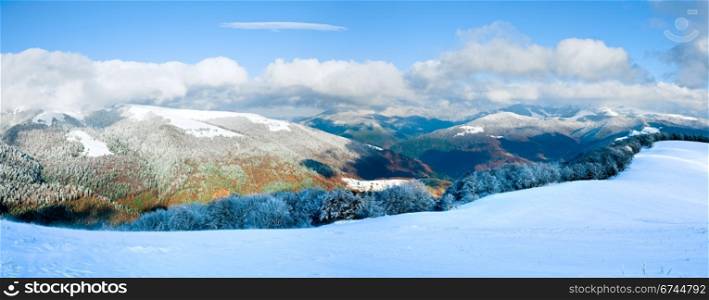October mountain beech forest edge with first winter snow and last autumn colourful foliage on far mountainside. Two shots stitch image.