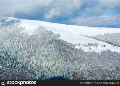 October mountain view with first winter snow and last autumn colorful foliage on far mountainside