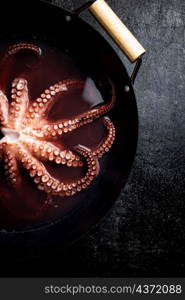 Octopus is boiled in a pot of water. On a rustic background. High quality photo. Octopus is boiled in a pot of water.