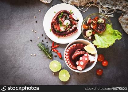 Octopus salad vegetables with lemon lime tomatoes chili herbs and spice on plate and bowl, Fresh and healthy salad seafood squid and octopus tentacles - top view 