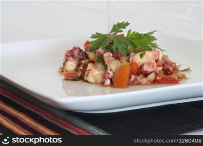 Octopus salad with peppers, onion and tomatos, with olive oil and vinegar.