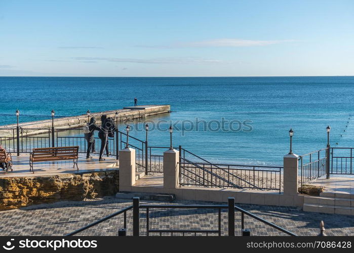 Odessa, Ukraine - 12.27.2018. Lonely people on the pier by the sea on a sunny winter day. Pier on the beach in winter day