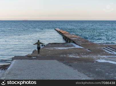 Odessa, Ukraine - 12.27.2018. Lonely people on the pier by the sea on a sunny winter day. Pier on the beach in winter day