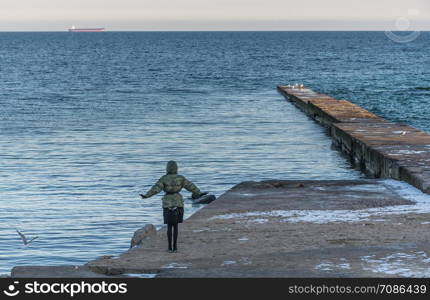 Odessa, Ukraine - 12.27.2018. Lonely people on the pier by the sea on a sunny winter day. Pier on the beach in winter day