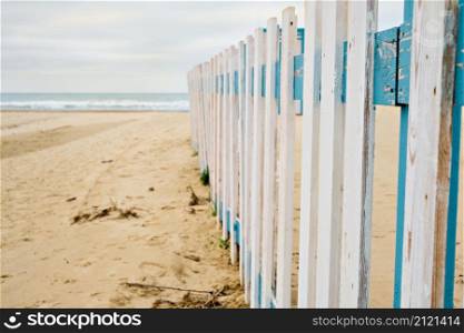Off-season rest. Deserted spring beach, fence in front of a public beach, cloudy sky waiting for rain. Off-season sea beach, place for text