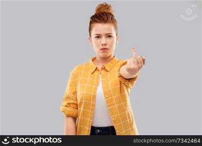 offensive gesture and people concept - angry red haired teenage girl in checkered shirt showing middle finger over grey background. red haired teenage girl showing middle finger