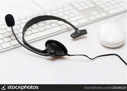 Office black headphones laying on white keyboard isolated