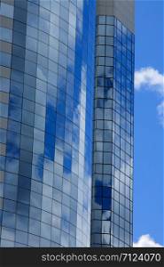 Office building windows reflect blue sky and clouds.