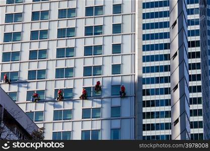 Office buildings modern facades and team of window cleaners in Warsaw downtown, Poland.