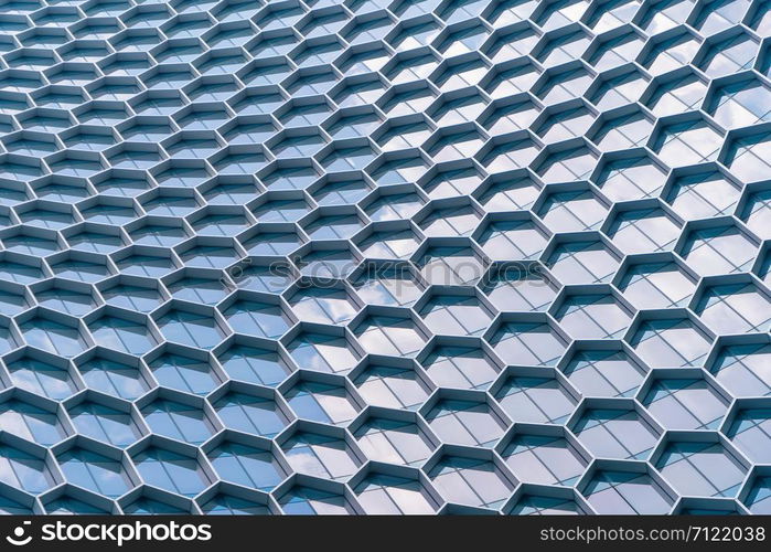 Office buildings. Structure of hexagon windows in futuristic technology network connection concept. Blue glass modern architecture facade design with reflection of sky in urban city, Downtown.