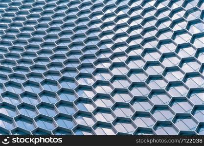Office buildings. Structure of hexagon windows in futuristic technology network connection concept. Blue glass modern architecture facade design with reflection of sky in urban city, Downtown.