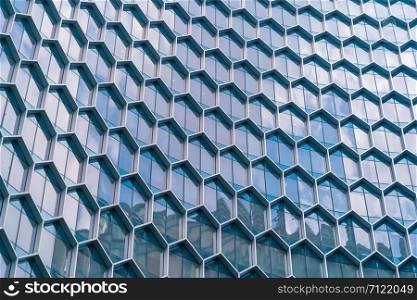 Office buildings. Structure of hexagon windows in futuristic technology network connection concept. Blue glass modern architecture facade design with reflection of sky in urban city, Downtown.