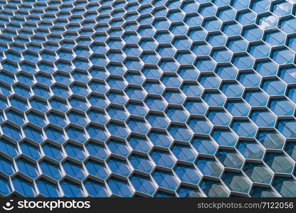 Office buildings. Structure of hexagon windows in futuristic technology network connection concept. Blue glass modern architecture facade design with reflection of sky in urban city, Downtown.