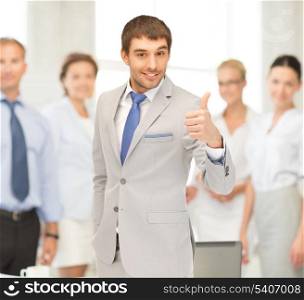office, buisness, teamwork concept - friendly young smiling businessman with thumbs up