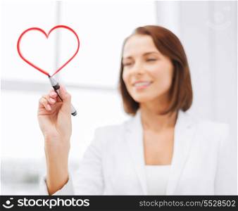 office, business and technology concept - businesswoman drawing heart in the air with marker