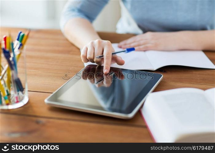 office, business, education, technology and internet concept - close up of student woman with tablet pc computer and notebook at home