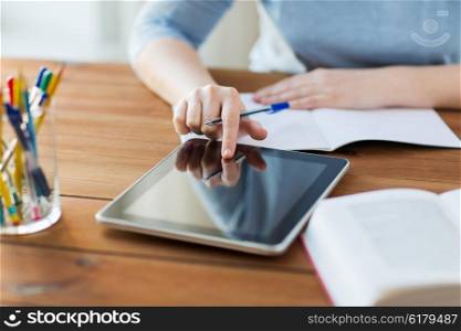 office, business, education, technology and internet concept - close up of student woman with tablet pc computer and notebook at home