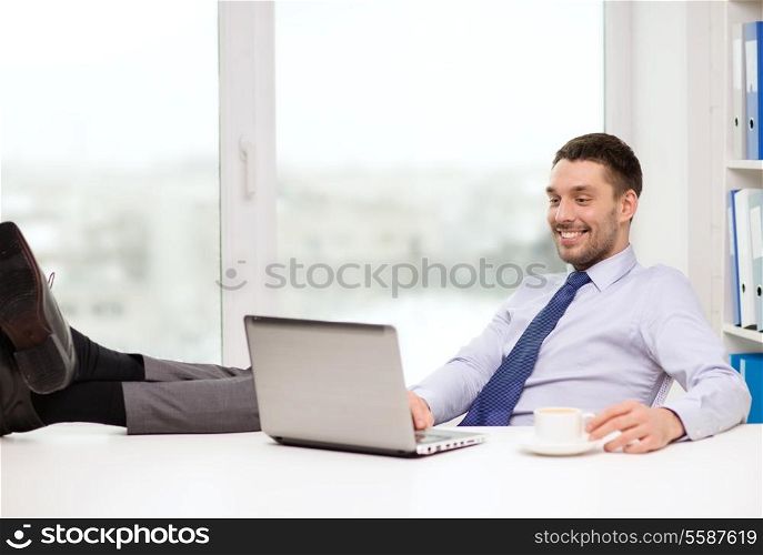office, business, education, technology and internet concept - smiling businessman or student with laptop computer and coffee at office