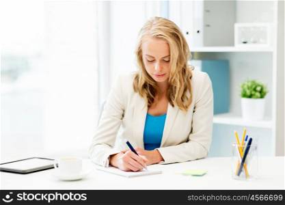 office, business, education, technology and internet concept - smiling businesswoman or student sitting at table and writing to notebook