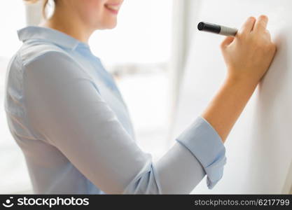 office, business, people and education concept - close up of woman with marker writing or drawing something on white board