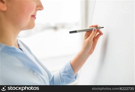 office, business, people and education concept - close up of woman with marker writing or drawing something on white board