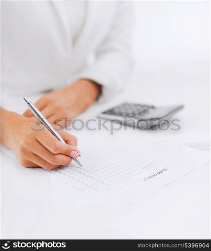 office, business, tax, accounting concept - businesswoman working with calculator in office