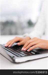 office, business, technology and internet concept - businesswoman using her laptop computer