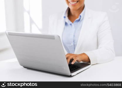 office, business, technology and internet concept - businesswoman using her laptop computer