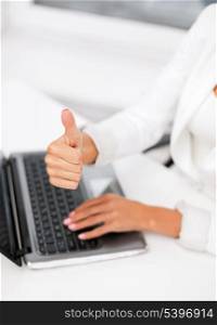 office, business, technology and internet concept - businesswoman with laptop computer showing thumbs up