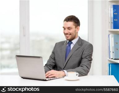 office, business, technology and internet concept - smiling businessman with laptop computer and coffee at office