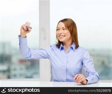 office, business, technology concept - businesswoman writing something in the air with marker