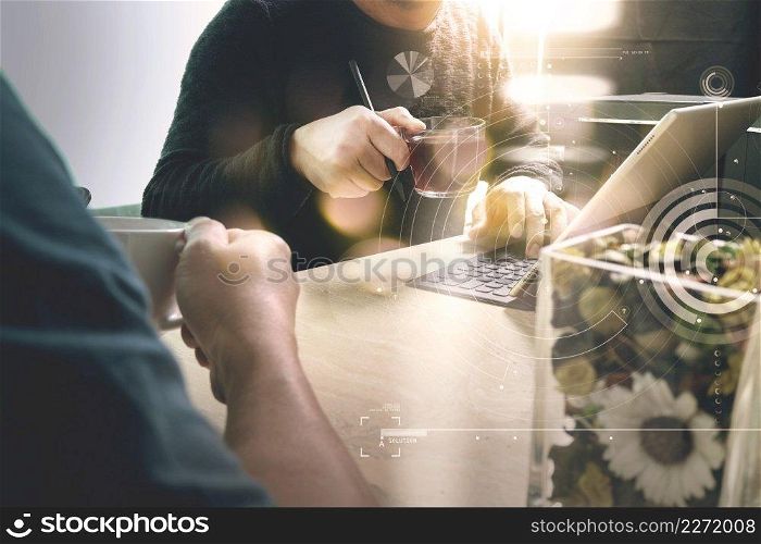 Office coffee break with two designer colleagues sitting chatting over cups of coffee,flower vase,digital tablet docking smart keyboard on marble desk,filters effect film  