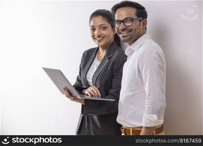Office colleagues smiling together while doing office work using laptop