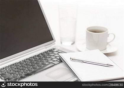 Office desk laptop with notepad and pen on white background