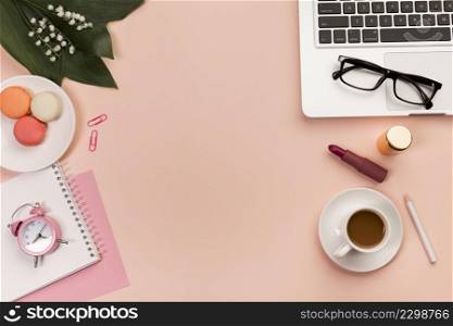 office desk with macaroons coffee cup makeup product eyeglasses laptop peach backdrop