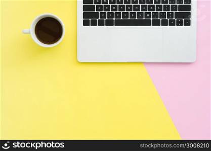 Office desk working space - Flat lay top view copy space of a working space with laptop, a coffee cup and little grass placing on pastel background. Pastel pink yellow color background space concept.