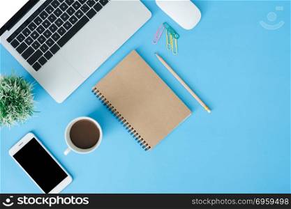 Office desk working space - Flat lay top view copy space of work. Office desk working space - Flat lay top view copy space of working space with laptop, blank notebook, coffee and smartphone placing on blue pastel copy space. Pastel blue background space concept.