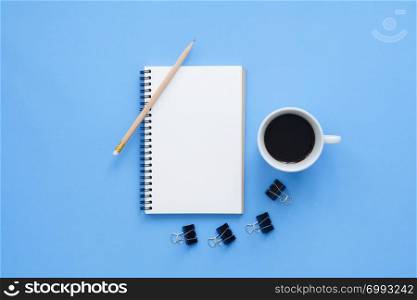 Office desk working space - Flat lay top view mockup of a working space with white blank notebook page, coffee cup on blue pastel background. Pastel blue color background space concept.