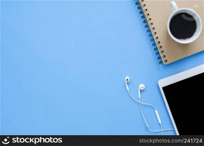 Office desk working space - Flat lay top view mockup photo of working space with smart device, coffee cup and notebook on blue pastel background. Pastel blue color copy space working desk concept.
