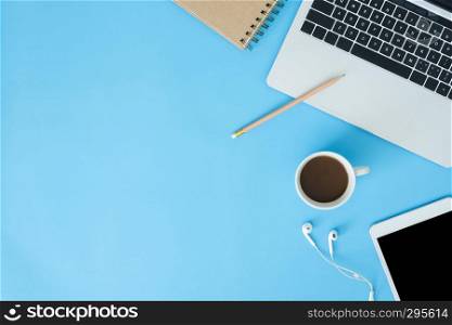 Office desk working space - Flat lay top view mockup photo of working space with laptop, smart device and a cup of coffee on blue pastel background. Pastel blue color copy space working space concept.