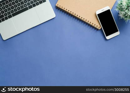 Office desk working space - Flat lay top view mockup photo of working space with laptop, smartphone and blank notebook on blue pastel background. Pastel blue color background working desk concept.