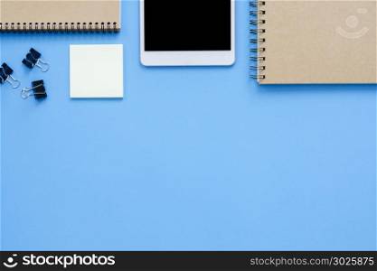 Office desk working space - Flat lay top view mockup photo of a working space with tablet, notebook, coffee and stationary on blue pastel background. Pastel blue color copy space working desk concept.