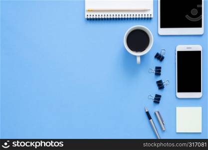 Office desk working space - Flat lay top view mockup photo of working space with tablet, phone, coffee cup and notebook on blue pastel background. Pastel blue color copy space working desk concept.