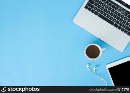 Office desk working space - Flat lay top view mockup photo of working space with laptop, smart device and a cup of coffee on blue pastel background. Pastel blue color copy space working space concept.