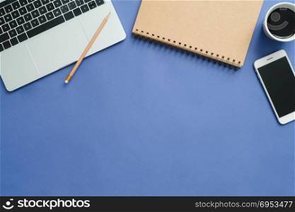 Office desk working space - Flat lay top view mockup photo of working space with laptop, smartphone, coffee up and notebook on blue pastel background. Pastel blue color background working desk concept