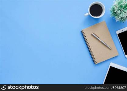 Office desk working space - Flat lay top view mockup photo of working space with tablet, phone, coffee cup and notebook on blue pastel background. Pastel blue color copy space working desk concept.