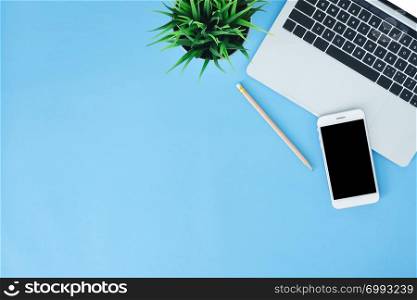 Office desk working space - Flat lay top view mockup photo of working space with laptop, smartphone and notebook placing on blue pastel background. Pastel blue color copy space working desk concept.