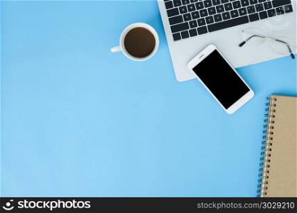 Office desk working space - Flat lay top view mockup photo of wo. Office desk working space - Flat lay top view mockup photo of working space with laptop, smartphone, coffee and stationary on blue pastel background. Pastel blue color copy space working desk concept.