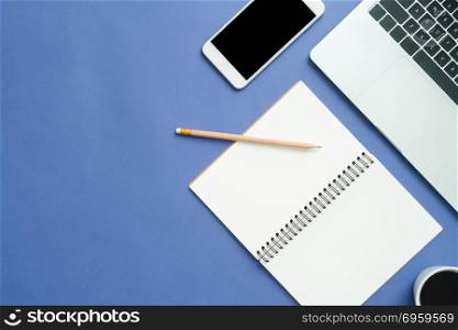 Office desk working space - Flat lay top view mockup photo of wo. Office desk working space - Flat lay top view mockup photo of working space with laptop, smartphone, coffee up and notebook on blue pastel background. Pastel blue color background working desk concept